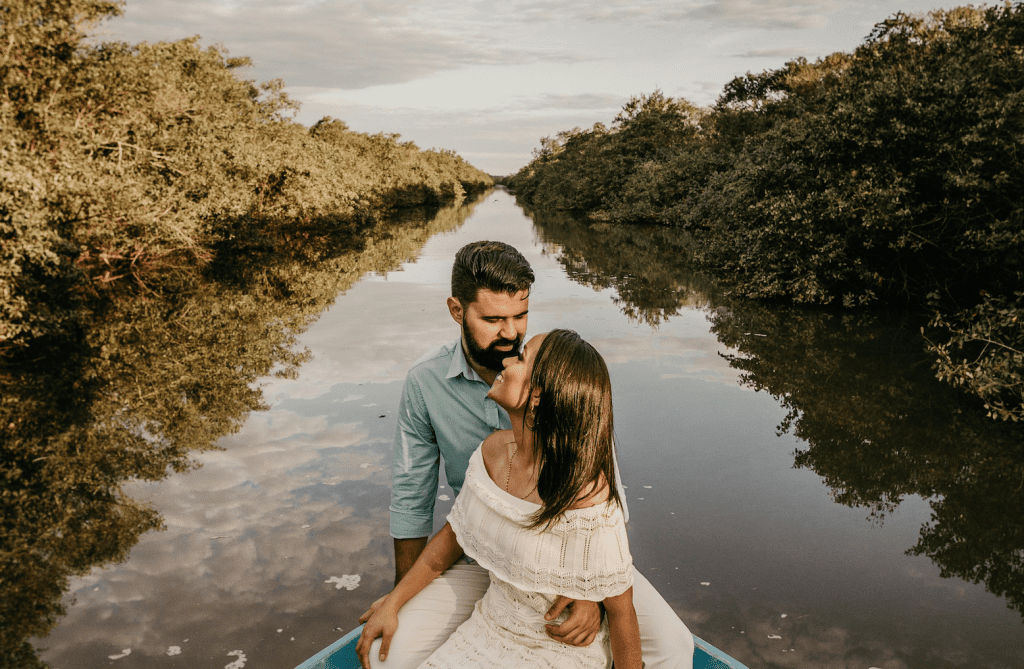 A couple in love sat together in a boat on water, love languages of quality time and physical touch