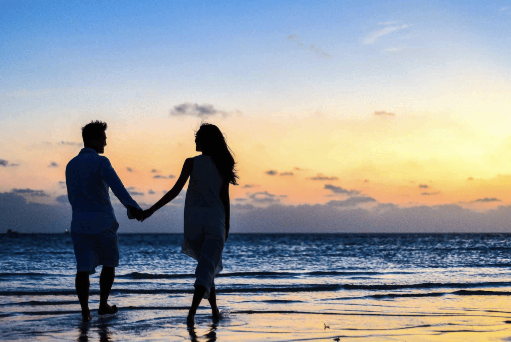 summer dating. couple holding hands on the beach at sunset