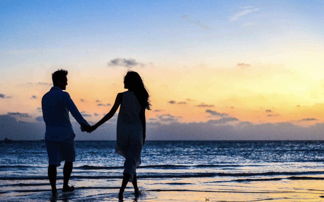 summer dating. couple holding hands on the beach at sunset